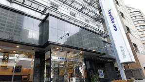 Un edificio moderno con entrada de vidrio, un letrero de 'Toyoko Inn' y una señal visible de 'AED'.