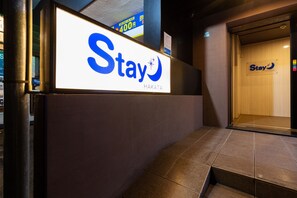 A hotel entrance with a 'Stay' sign, a staircase, and a door with the same branding. - Stay Hakata (Fukuoka)
