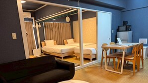 Et hotelværelse med seng, sofa, spisebord med stole, mikroovn og køleskab.