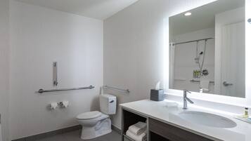 Un baño moderno con inodoro, bidé y un espejo grande sobre el lavabo.