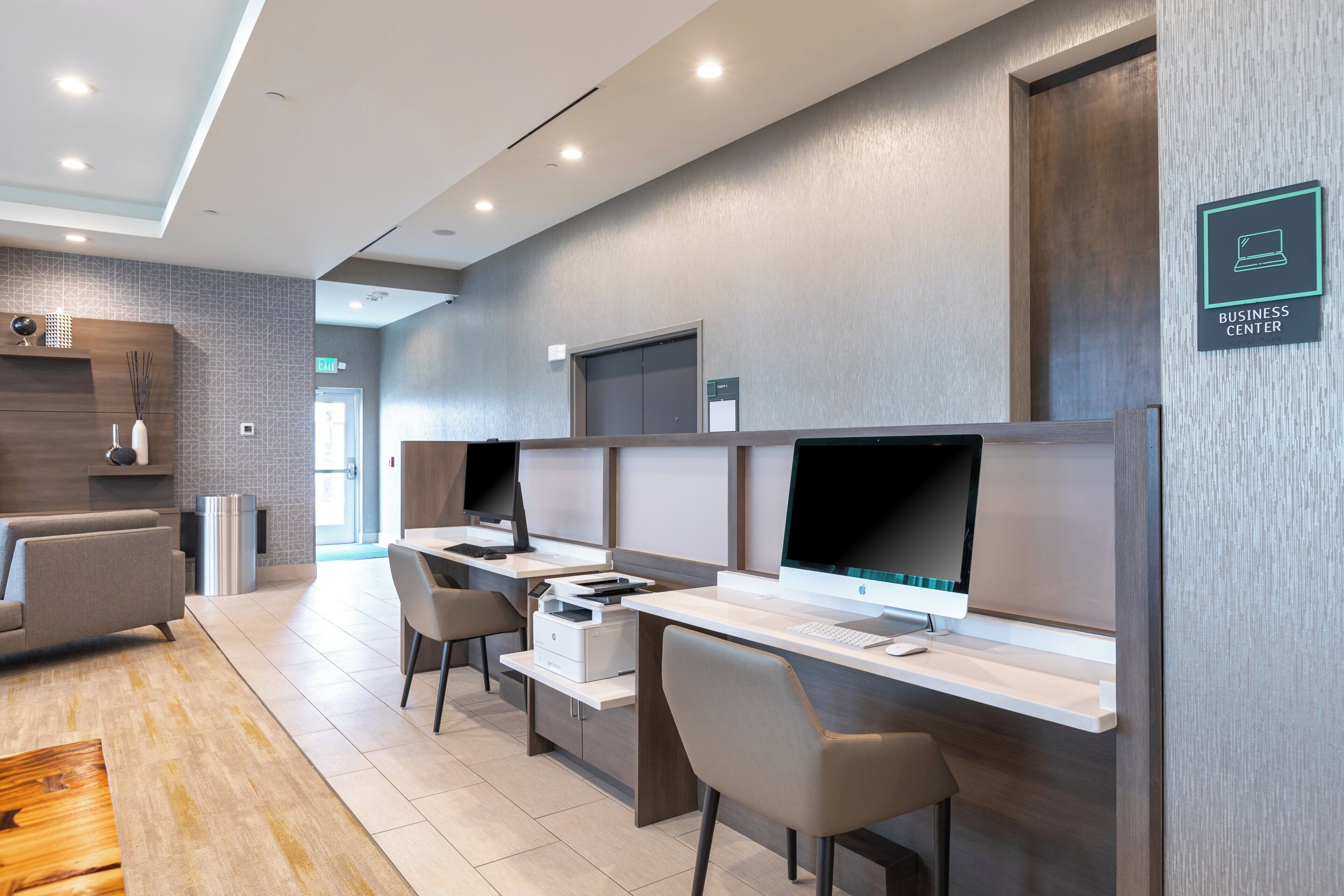 A modern business center with multiple computer stations, a reception desk, and a waiting area with a sofa.