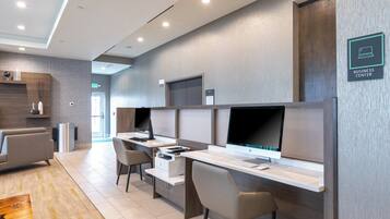 A modern business center with multiple computer stations, a reception desk, and a waiting area with a sofa.