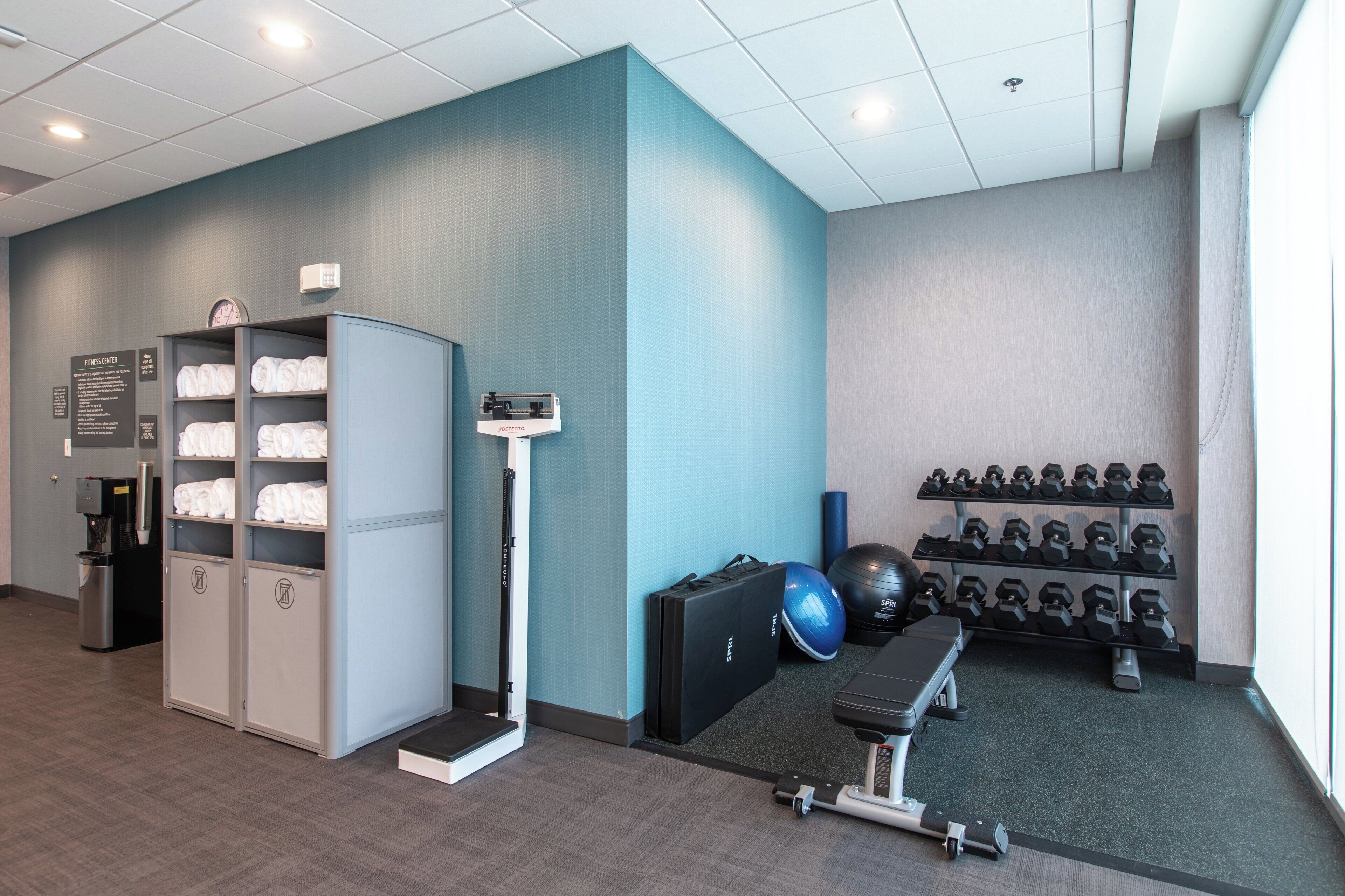 A fitness center with a water dispenser, a treadmill, exercise balls, and dumbbells.