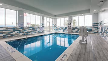 Une piscine intérieure avec une signalisation claire, notamment les panneaux « Eau peu profonde, il est interdit de plonger » et « Absence de maître-nageur. Baignez-vous à vos propres risques. »