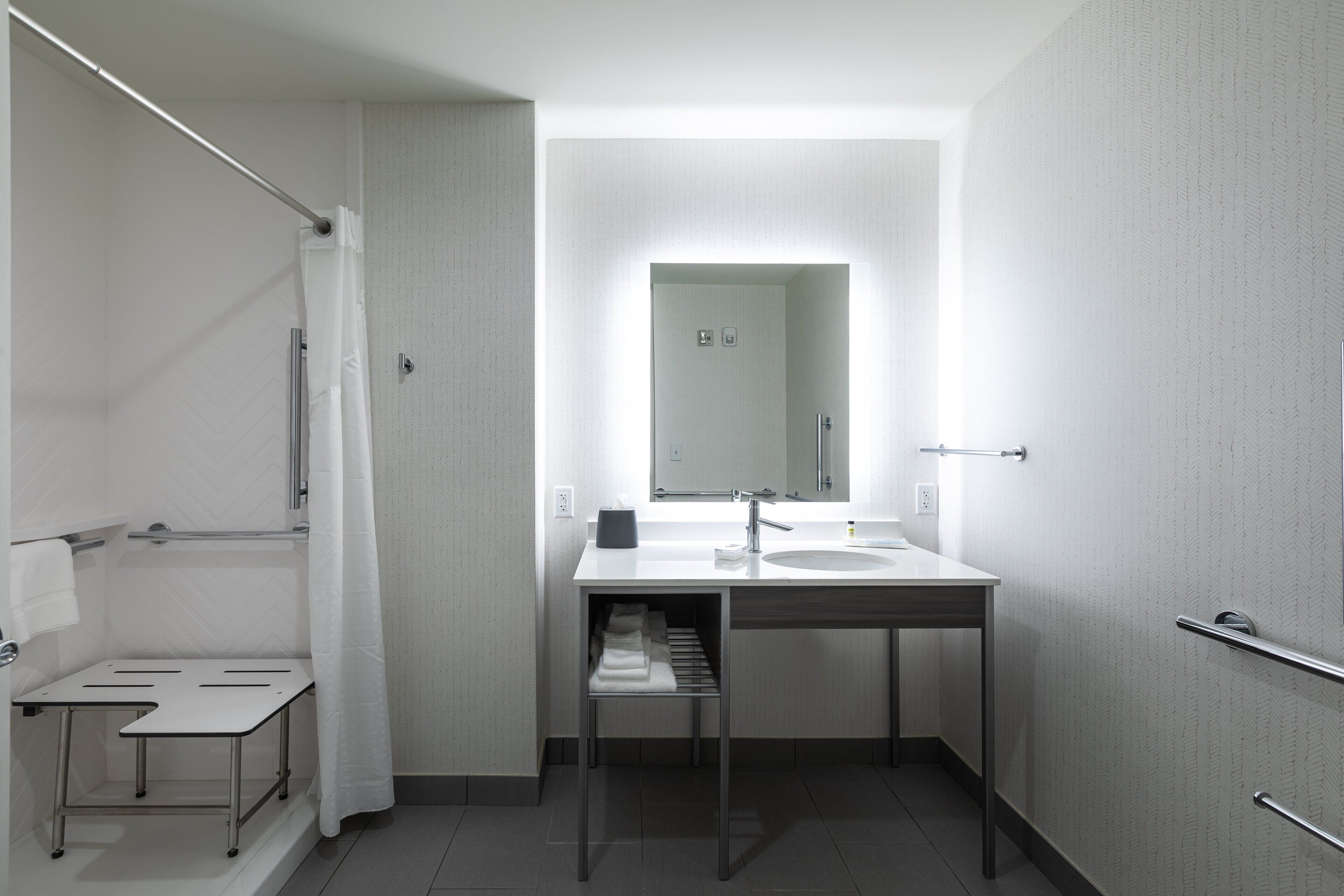A modern bathroom with a shower, a sink, and a mirror.