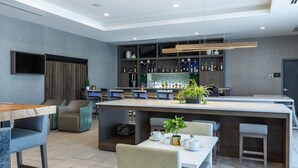 Zona de bar moderna con una barra alargada, asientos y una variedad de botellas.