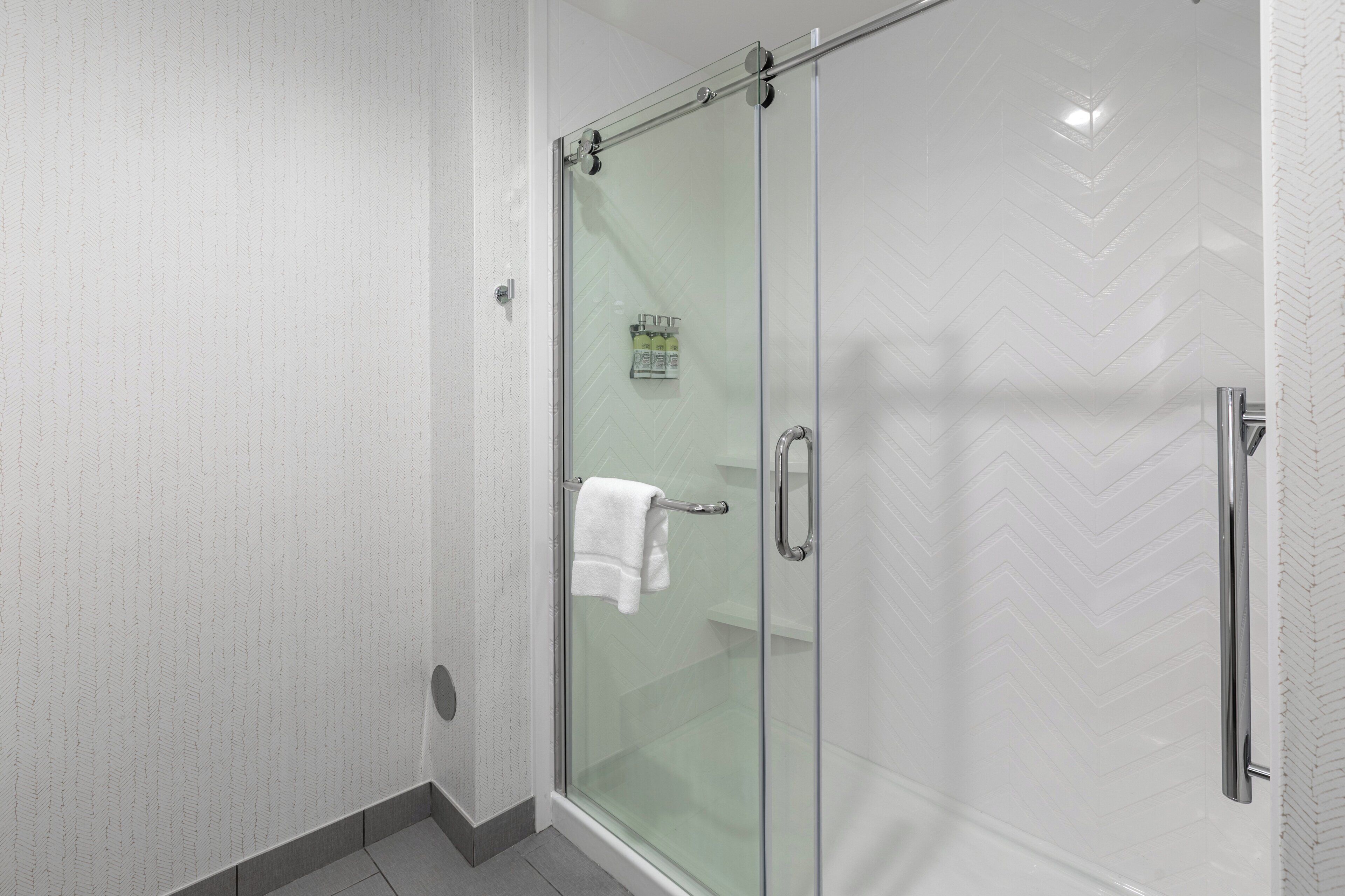 A glass-enclosed shower with a towel rack and a glass door.