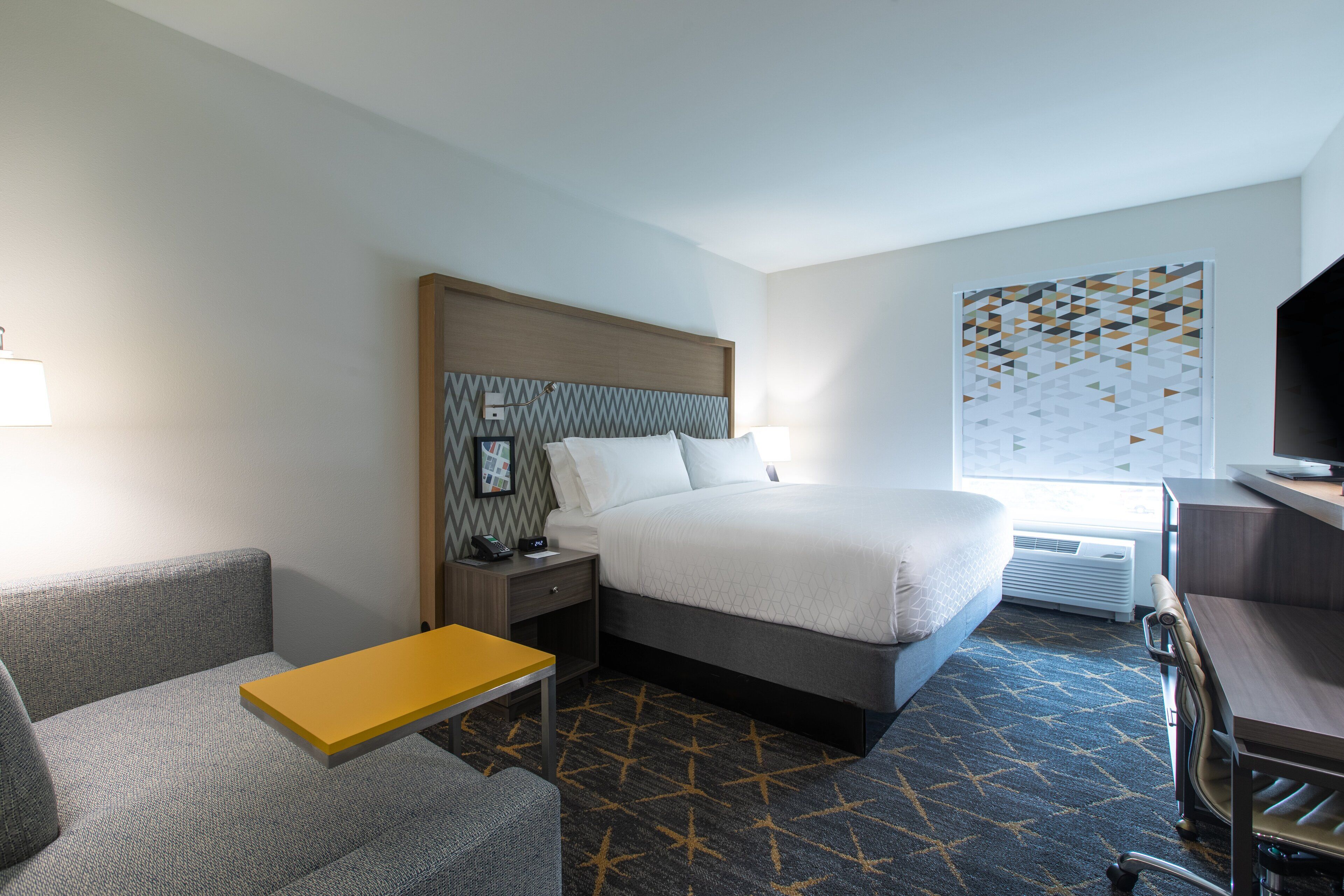 Una habitación de hotel con cama, escritorio, sillón, sofá y una pequeña mesa.
