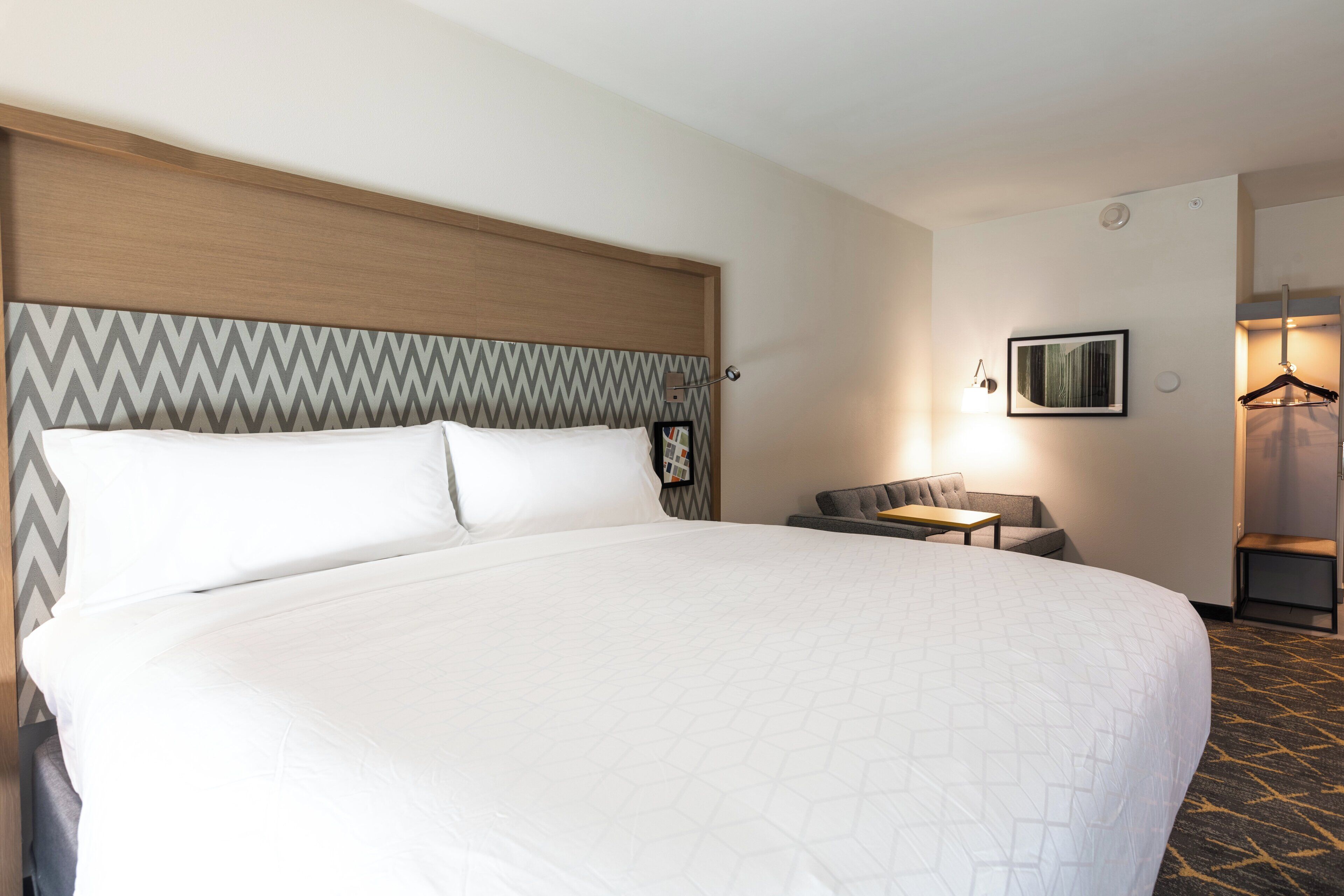 Une chambre d’hôtel avec un grand lit, une petite table, une chaise et une armoire.