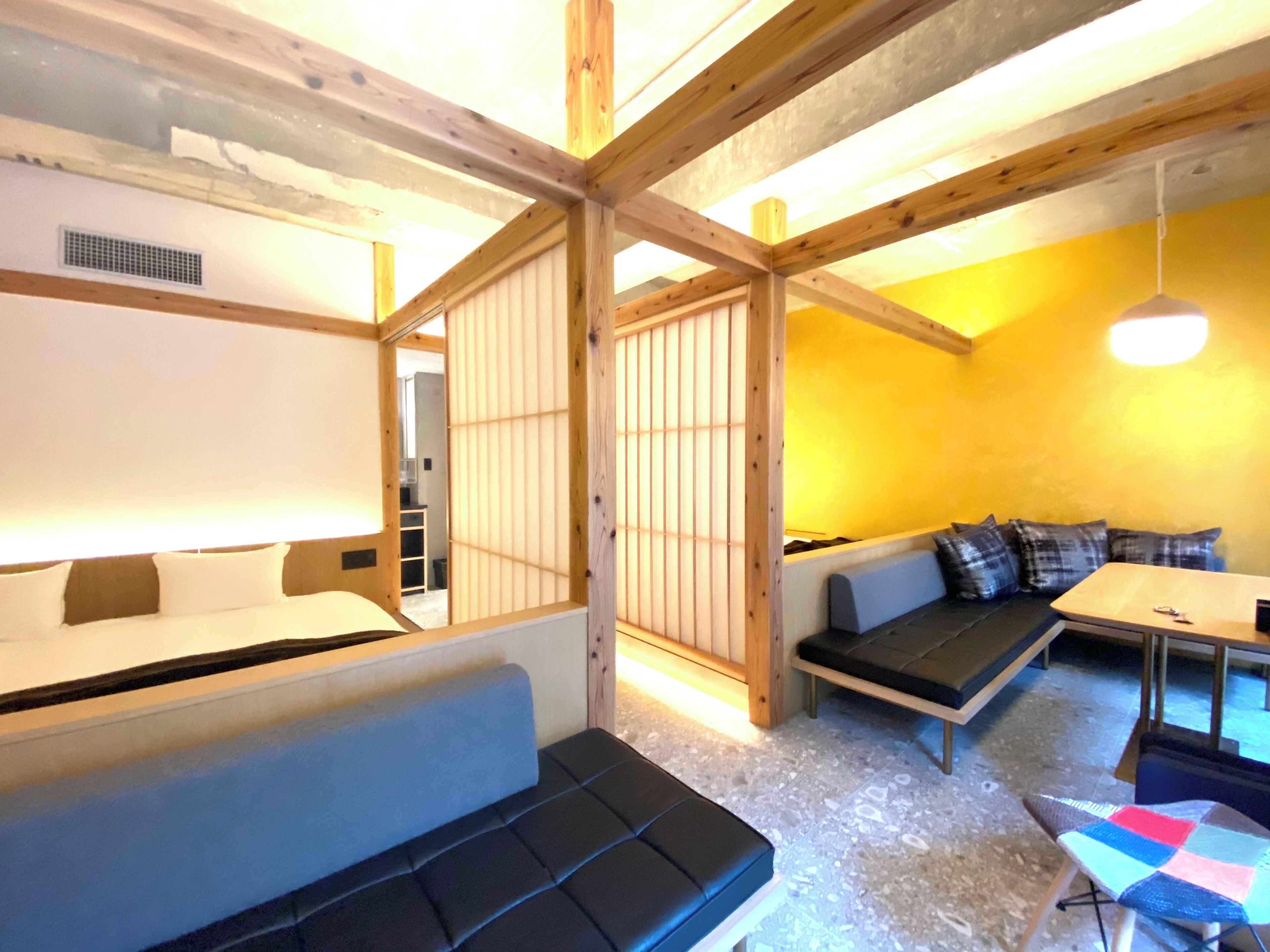 A room with a wooden ceiling, a sofa, a small table, and a bench.