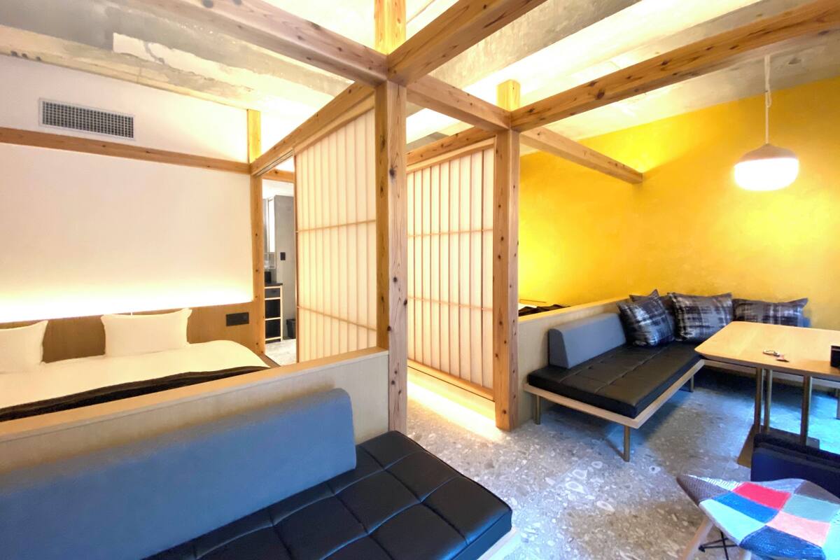 A room with a wooden ceiling, a sofa, a small table, and a bench.