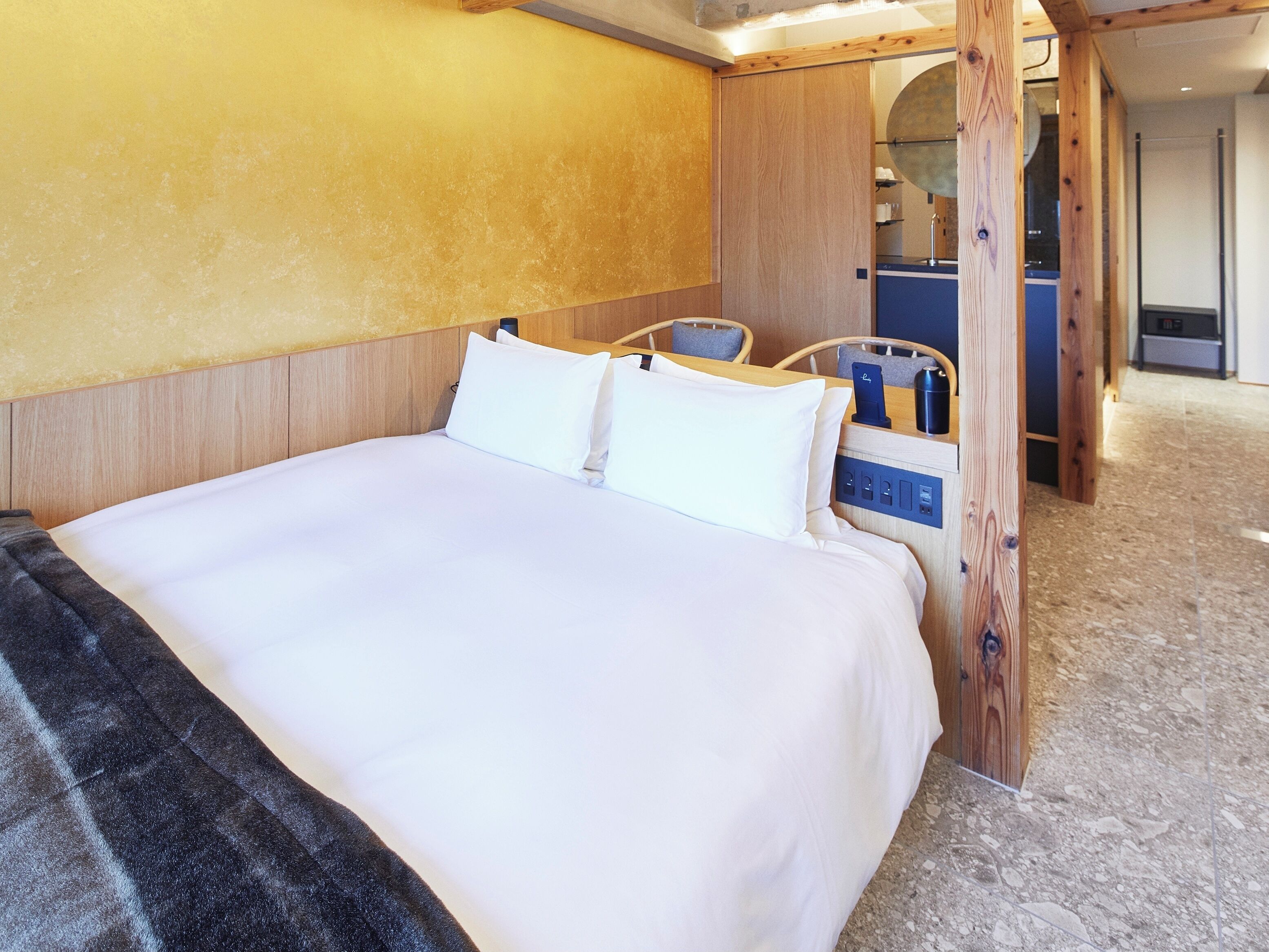 A hotel room with a large bed, wooden headboard, and a small desk with a chair.