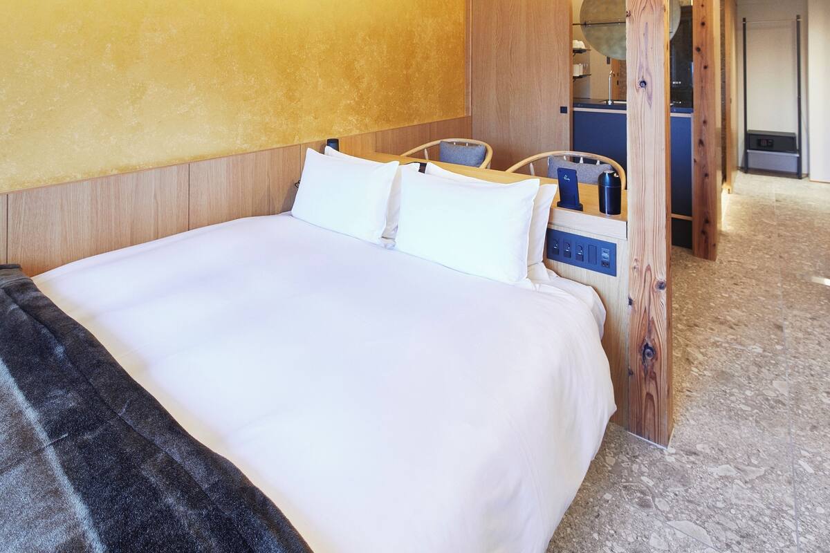A hotel room with a large bed, wooden headboard, and a small desk with a chair.