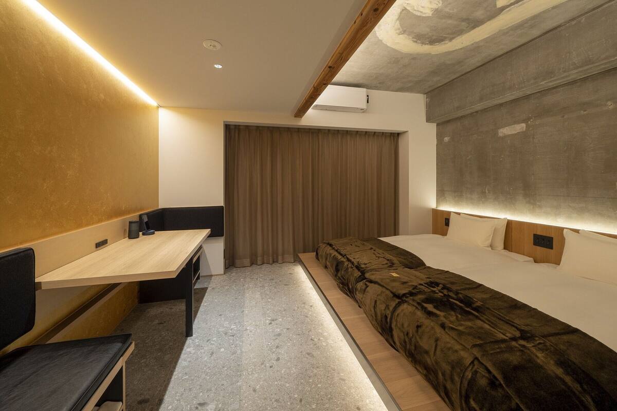 A compact hotel room with a bed, a desk, and a chair.
