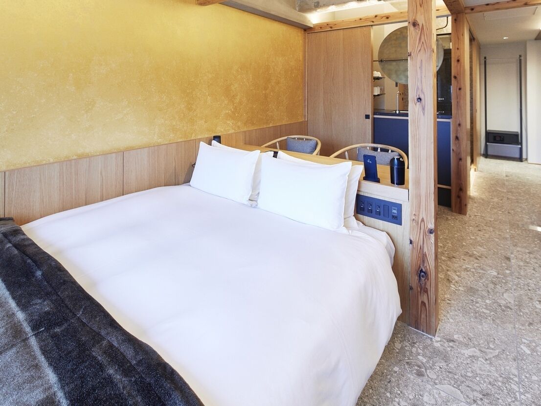 A hotel room with a large bed, wooden headboard, and a small seating area with a chair and table.