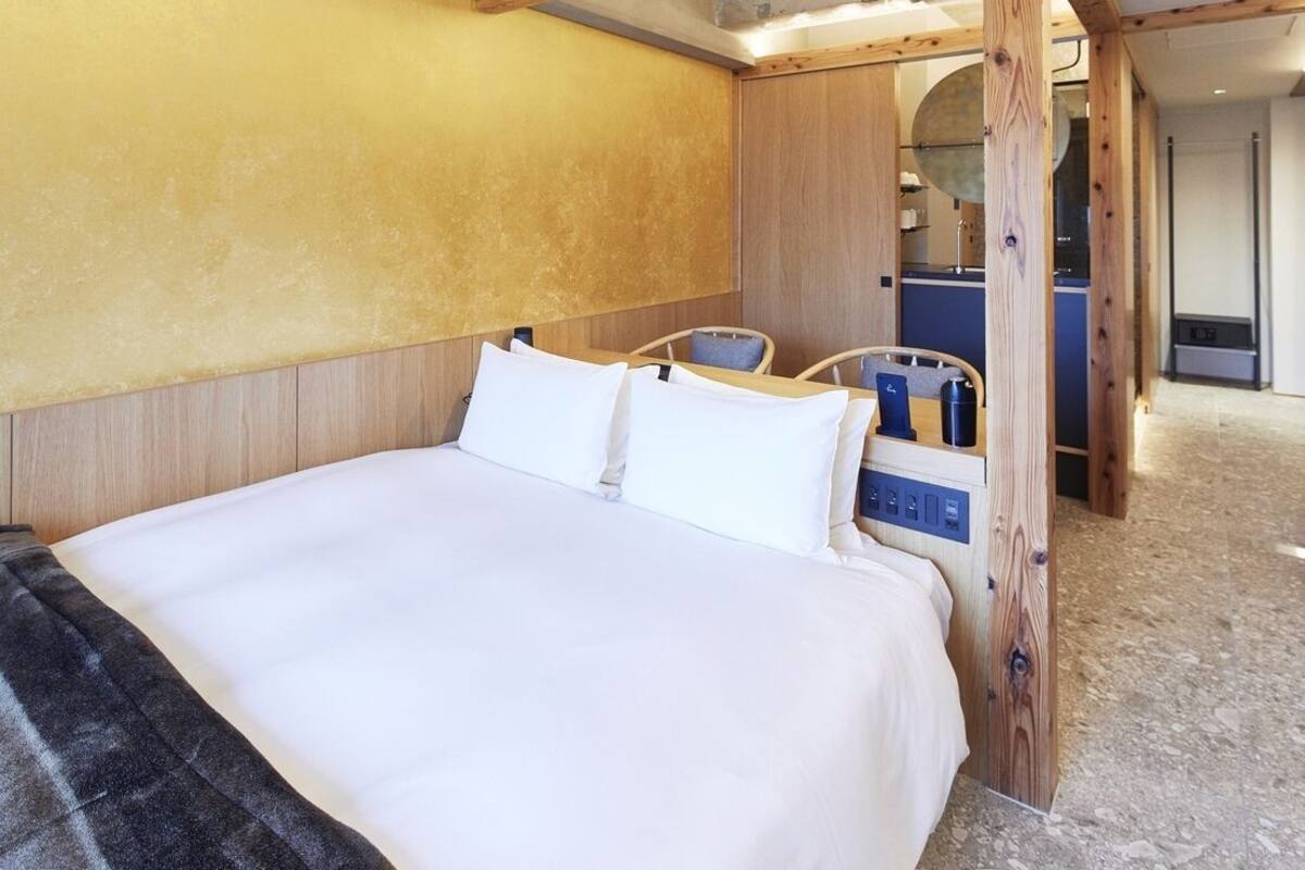 A hotel room with a large bed, wooden headboard, and a small seating area with a chair and table.