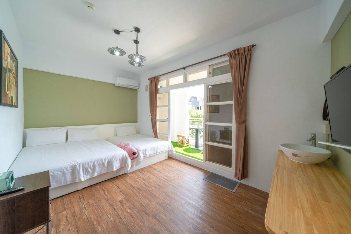 Une chambre à coucher comprenant un lit, une table de chevet, une fenêtre avec des rideaux, un lavabo et un luminaire au plafond.