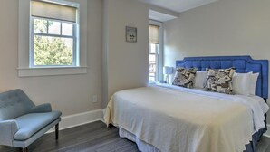 A bedroom with a bed, a chair, and a ceiling fan. - Charming Condo over City Bakery (Asheville)