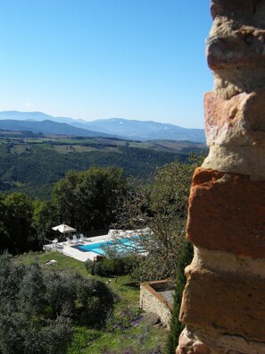 A pool area with a view of distant mountains. - Nice apartment for 2 guests with WIFI, pool, TV and pets allowed, close to San Gimignano (Volterra)