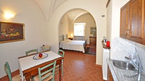 Une pièce confortable comprenant une table à manger, des chaises, un lit et un coin cuisine.