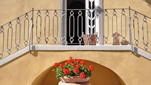 A building facade with a balcony, a large terracotta pot with red flowers, and two wall-mounted lanterns. - Lovely apartment for 2 people with WIFI, pool, TV and pets allowed, close to San Gimignano (Volterra)