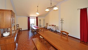 A spacious dining area with a large wooden table, multiple chairs, and a long bench. There are two pendant lights hanging from the ceiling. - Lovely apartment for 2 people with WIFI, pool, TV and pets allowed, close to San Gimignano (Volterra)