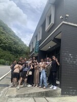 Un grupo de personas de pie frente a un edificio con un letrero verde.