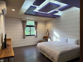 Un dormitorio con cama, escritorio, ventana e iluminación geométrica en el techo.