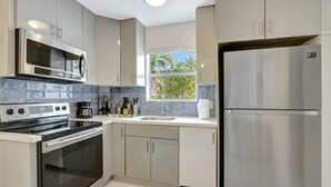 Una cocina moderna con electrodomésticos de acero inoxidable, una ventana y vistas a árboles.