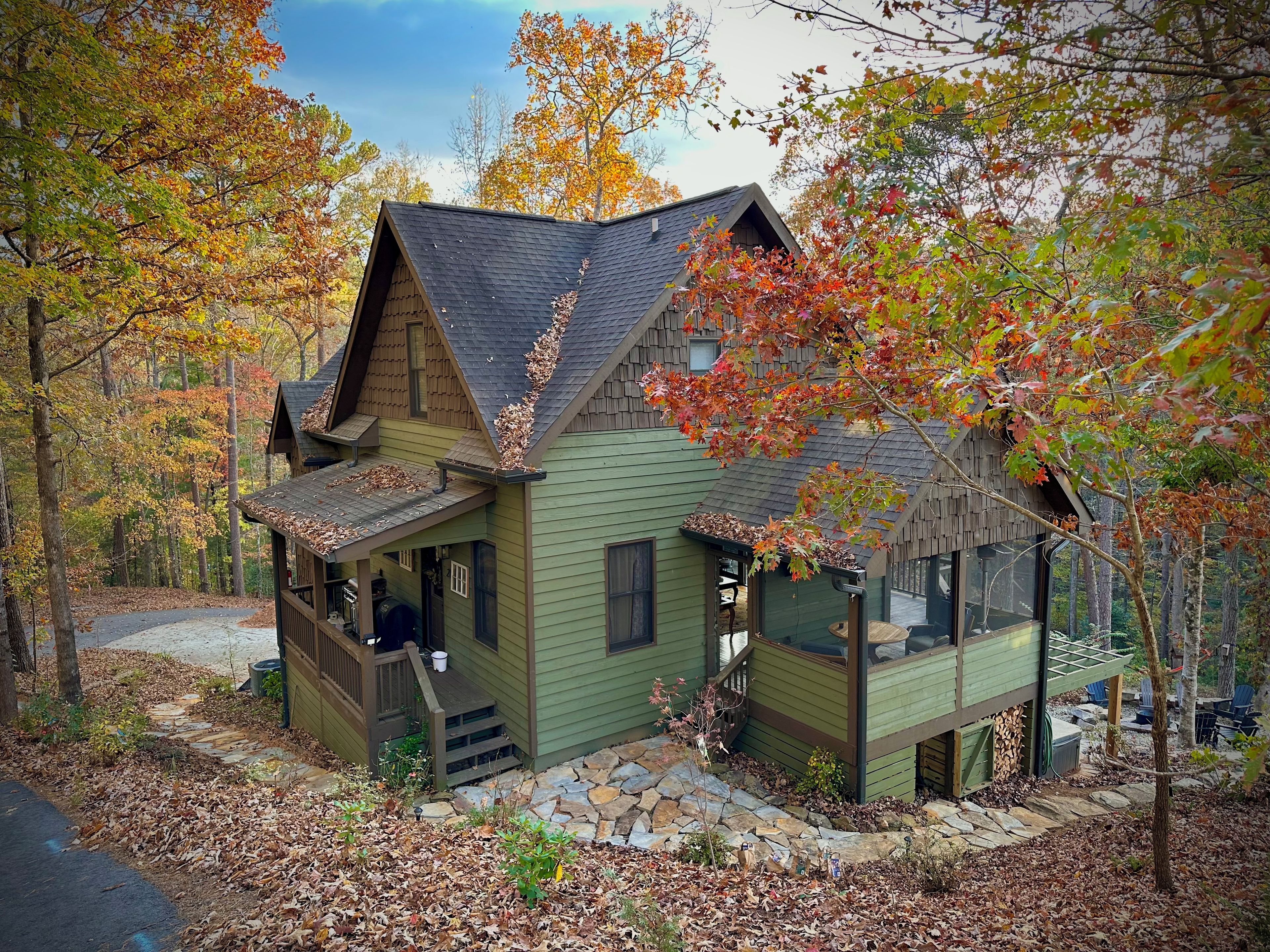A cabin with a porch, a stone pathway, and a forested backdrop.