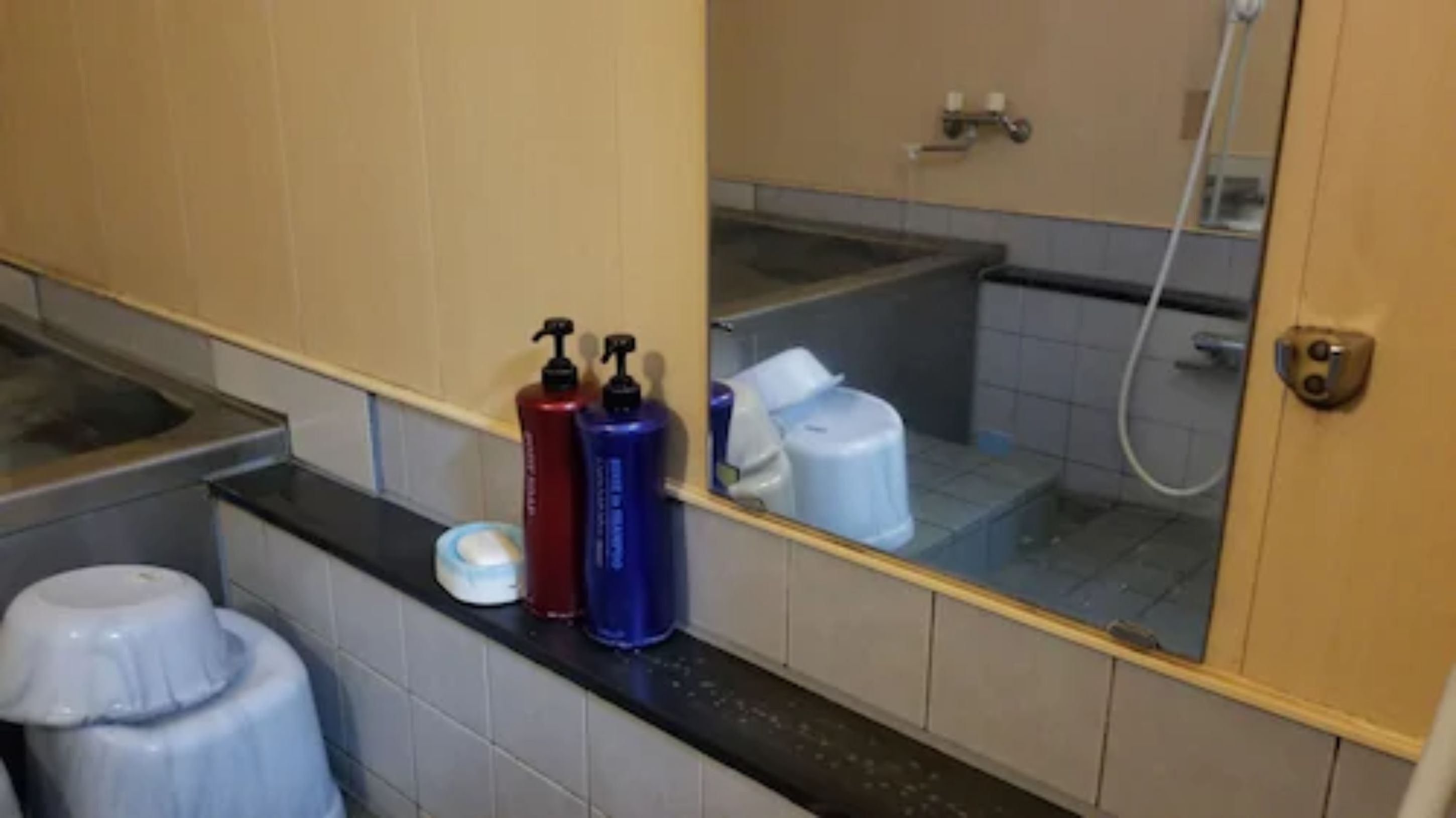 Een badkamer met een spiegel, een wastafel en toiletartikelen op het aanrecht.