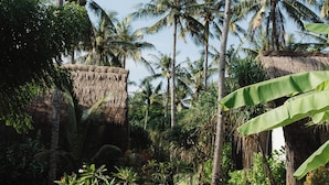 A pathway leading through a tropical garden with palm trees and a thatched-roof structure. - Lumi Hotel Gili Trawangan (Gili Trawangan)