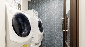 Une buanderie équipée de deux machines à laver à chargement frontal et ornée d’un mur à motifs.
