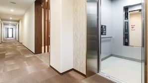 Un ascenseur moderne doté d’un écran numérique et d’une porte en verre transparent.