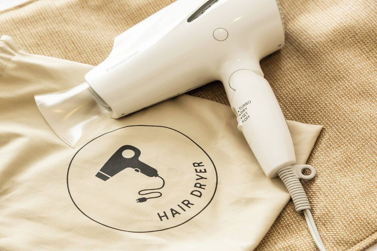 A hair dryer and a beige cloth with a logo.