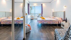 Et moderne hotelværelse med to senge, en balkon og havudsigt.