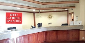 A reception area with a desk, a clock, and a sign for Red Carpet Inn & Suites. - Red Carpet Inn & Suites (Penns Grove)