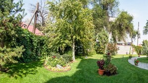 A garden with a bench, a pathway, and a building with steps. - Hotel Asia Mountains 2 (Bishkek)
