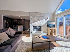 A modern living room with a fireplace, a sofa, a coffee table, and a TV.