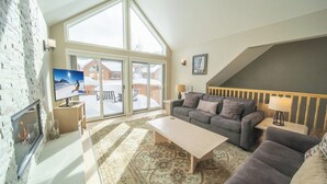 Amplia sala de estar con chimenea, ventana grande y televisor.