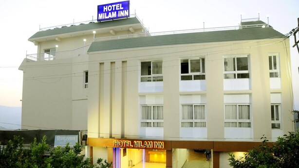 Un hôtel avec une enseigne bien visible indiquant « HÔTEL MILAM INN » et une entrée bien éclairée.