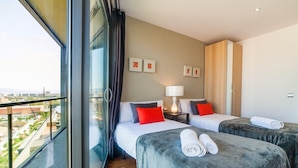 Una camera d'hotel con due letti, un'ampia finestra e vista sulla città.