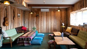 Una habitación acogedora con paredes de madera, un sofá verde, cojines azules, una mesa de centro de madera y un sofá de cuero marrón.