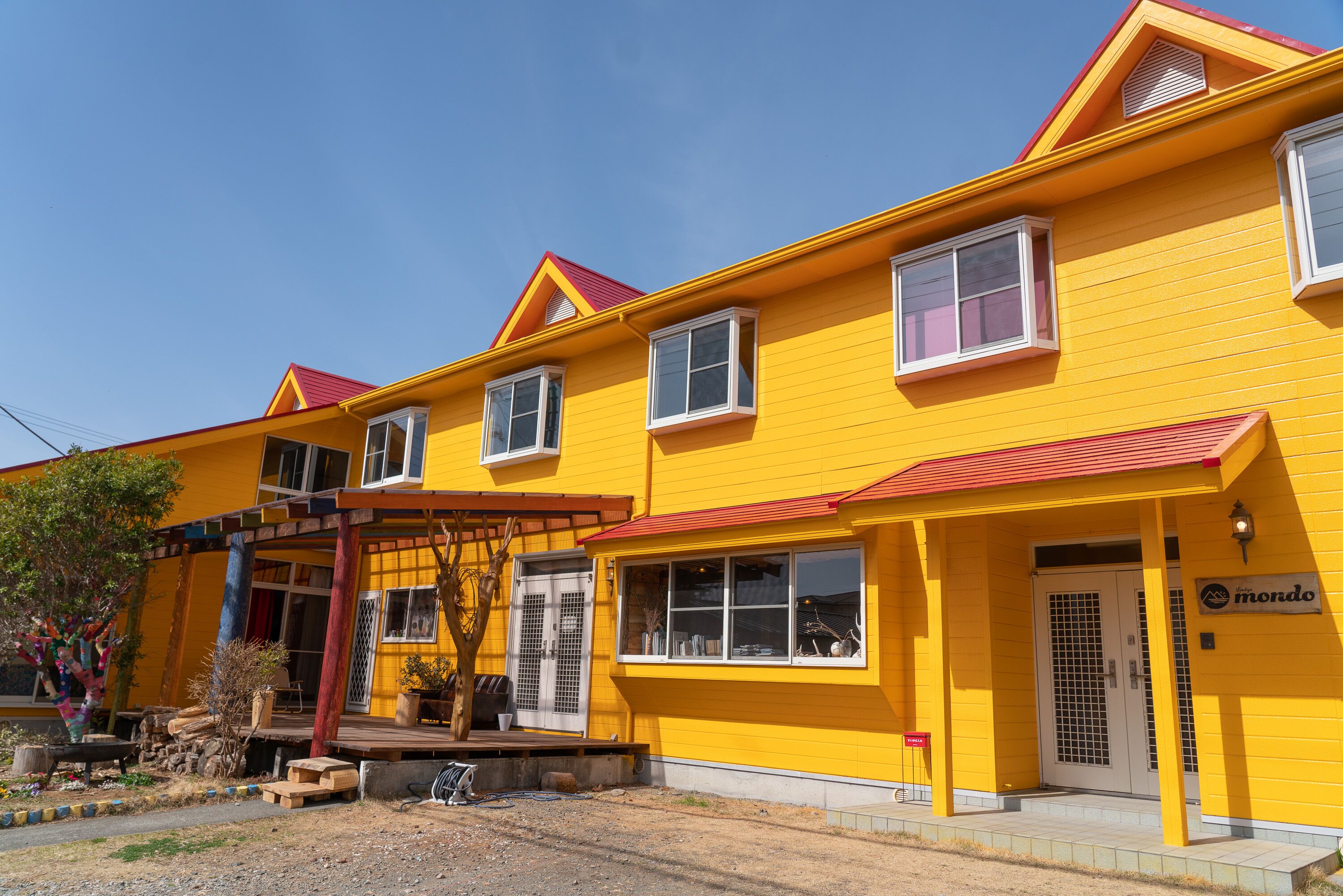 A yellow building with a red roof, multiple windows, and a door labeled "mondo".
