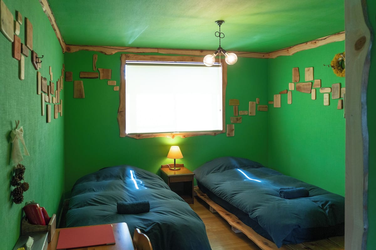 A room with two beds, a window, a lamp, and wall decorations.