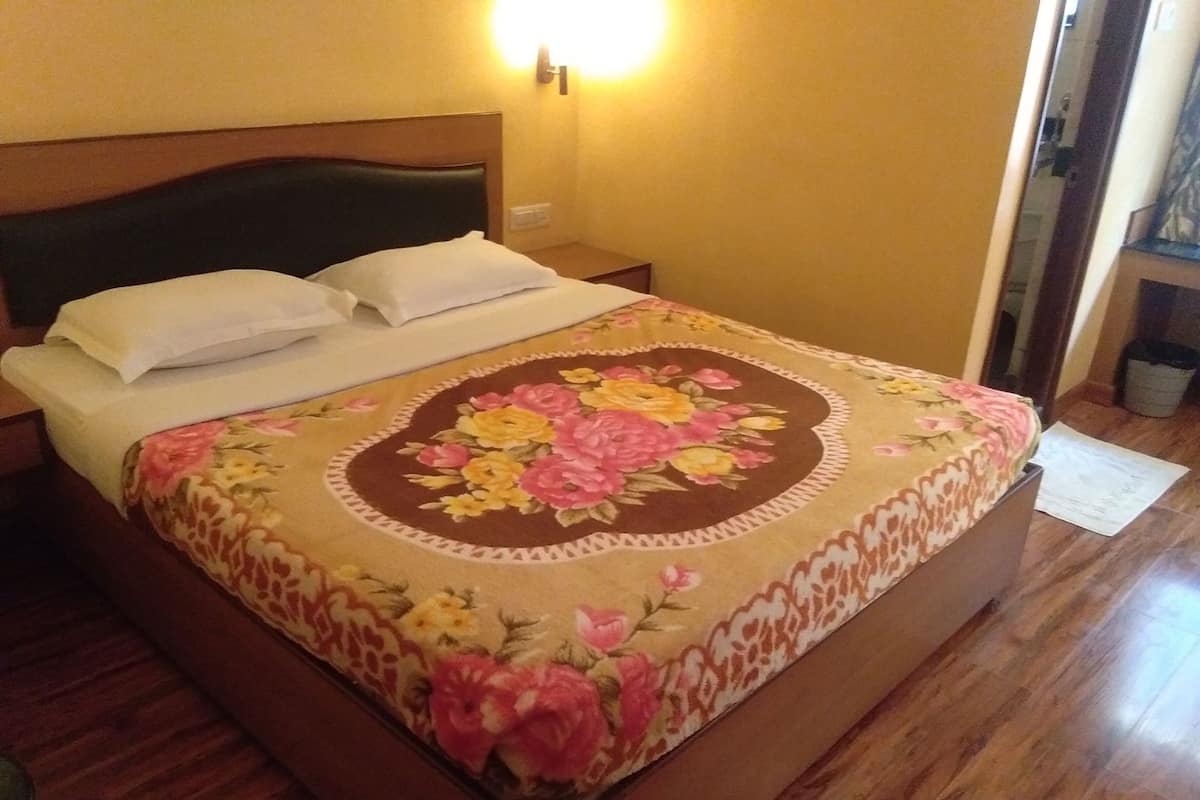 Una cama con una colcha estampada, un cabecero de madera y una mesita de noche con una lámpara.