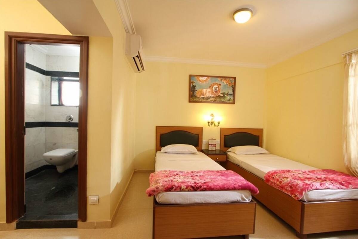Habitación de hotel con dos camas, un cuadro en la pared y un baño visible a través de una puerta abierta.