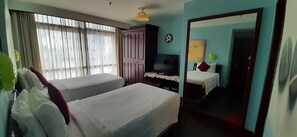 A hotel room with two beds, a TV, a wardrobe, and a mirror.