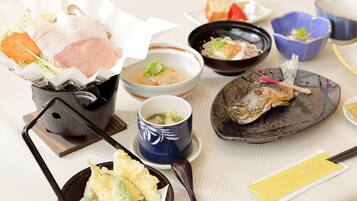 A variety of Japanese dishes including sushi, sashimi, and tempura, served on traditional ceramic and lacquerware.