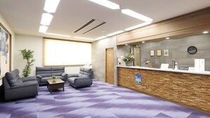 A reception area with a wooden reception desk, a clock, and a seating area with sofas and a coffee table. - Hotel Granjam Tsugaike (Otari)